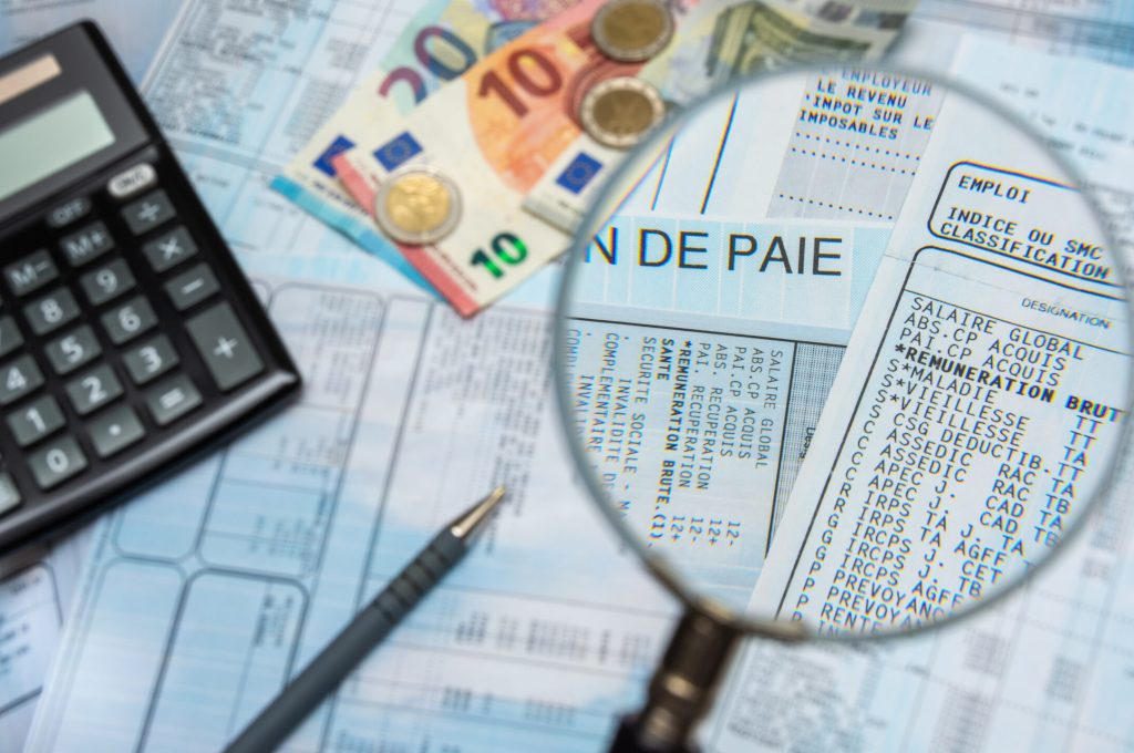 Bulletin de paie français à la loupe, avec argent en euros, calculette et stylo